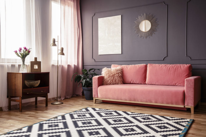 Side angle of a living room interior with a powder pink sofa, pa